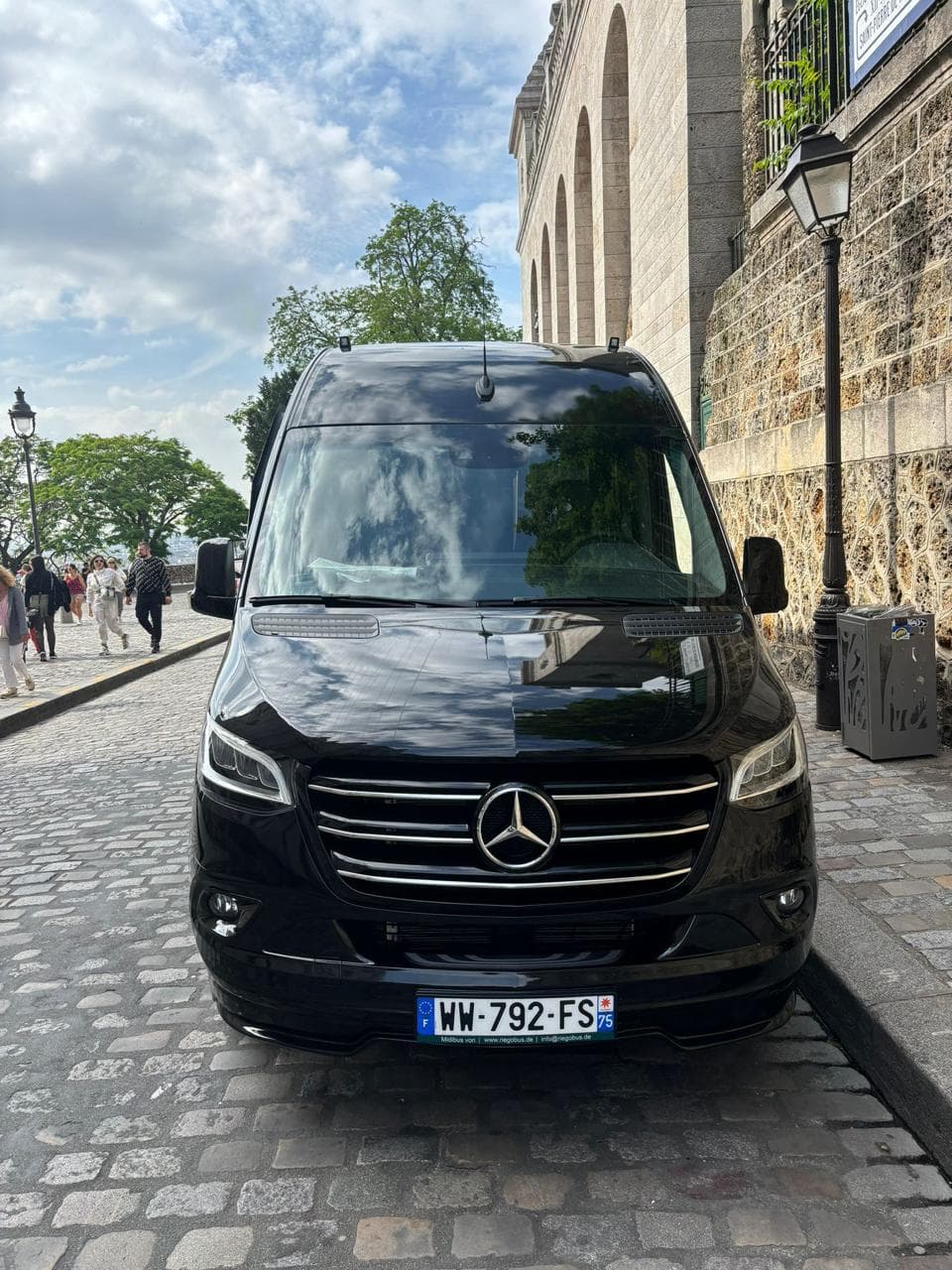 Minibus Mercedes Sprinter noir de face, rue pavée à Montmartre