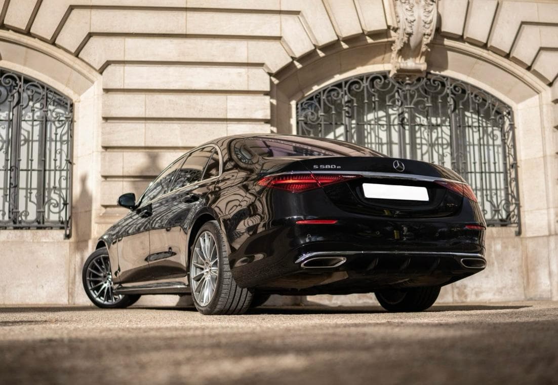 Berline Mercedes Classe S noire de trois quarts arrière, devant une façade haussmannienne
